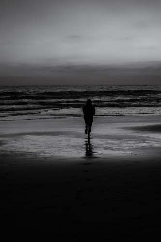  man in black jacket walking on beach during daytime 